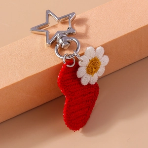 Detail shot of a knitted red heart and daisy flower keychain with star metal clasp