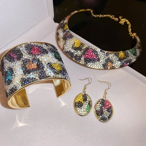 Macro shot of gold jewelry set with colorful crystals and leopard pattern inlay