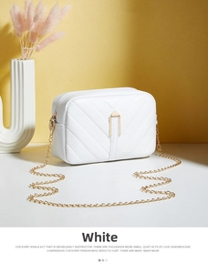 Detailed view of white rectangular crossbody bag with V-shaped quilting and gold chain strap
