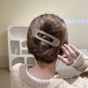 Close-up of a model wearing a large khaki oval acrylic hair clip for elegant styling