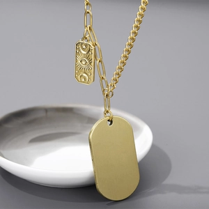 Détail du collier en acier titane doré avec pendentifs gravés œil et ovale poli
