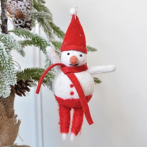 Handmade wool felt snowman ornament with red hat hanging on a snowy Christmas tree