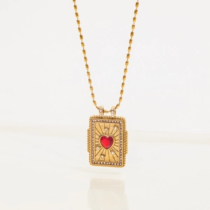 Macro detail of gold necklace with red heart stone and sparkling crystal sunburst frame