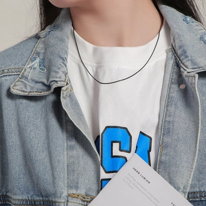 Detail shot of a slim black snake chain necklace worn with a casual denim jacket