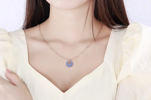 Detail of rose gold zodiac necklace featuring a blue enamel crescent moon and star pendant