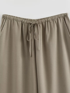 Detail of taupe trousers showing elastic waistband with drawstring and side pocket