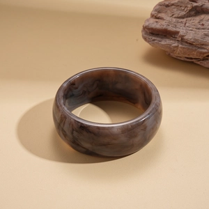 Macro shot of wide resin bangle with smoke marble texture and polished brown gray finish
