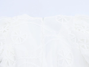 Détail de robe française blanche avec broderie ajourée et fermeture éclair cachée