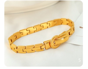 Nahaufnahme eines goldenen Titanstahl-Armbands mit Vintage-Gürtelschnalle auf Seide