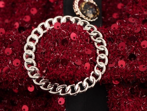 Dettaglio del tessuto tweed rosso con catena in metallo argento e paillettes lucide