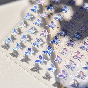 Macro detail of blue-purple gradient butterfly nail art stickers with laser finish