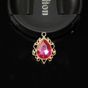 Vue macro d'un pendentif goutte en alliage doré avec une pierre précieuse rose