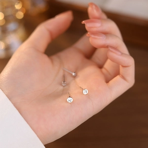 Minimalist S925 sterling silver cross stud earrings shown in palm for size scale
