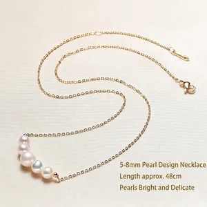Minimalist gold chain necklace featuring five 5-8mm freshwater pearls on beige fabric