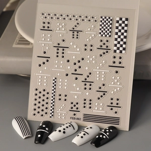 Macro detail of 3D checkerboard nail art stickers featuring domino and dot patterns