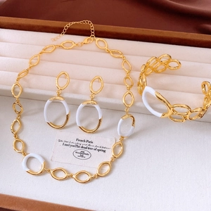 Detail of gold chain necklace and bracelet set with white enamel inlay on jewelry tray