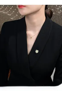 Close-up of four-leaf clover brooch with white petals on a black blazer collar