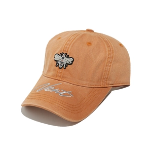 Detailed close-up of bee embroidery and 'Nice' script on orange cotton baseball cap