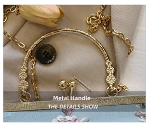 Detail view of ornate gold floral handle and embroidery on vintage chain handbag
