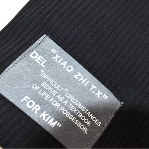 Detailed close-up of black waffle knit fabric texture and grey sewn-on brand label