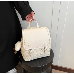 Détail d'un sac à dos beige avec motifs d'ours et pendentif canard en peluche sur le côté