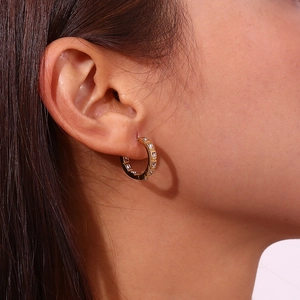 Close-up of 18K gold-plated hoop earrings featuring square-cut cubic zirconia on model