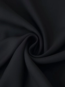 Close-up of black textile fabric showing fine fiber texture and elegant spiral folds