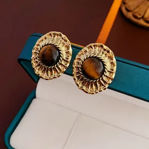 Detailed close-up of vintage metal texture and brown tiger eye stone on retro earrings