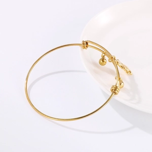 Adjustable golden stainless steel bangle with circular beads and charms on white plate