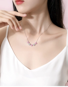 Detail of S925 silver necklace with pink and white floral pendants on model neckline