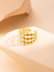 Detail of a triple-layer gold hollow ring featuring three small white pearls on a display