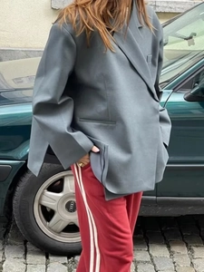 Detailed side view of grey oversize blazer with side slits and red side-striped sport pants