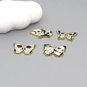 Gothic skull butterfly pendants with gold metal edges and black and white enamel finish