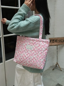 Pink quilted tote bag with floral print and large capacity being worn by a model