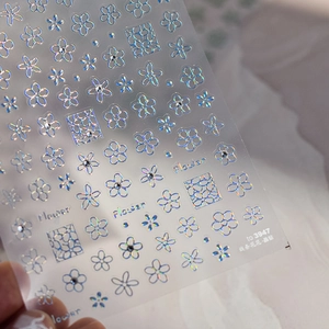 Gros plan de stickers holographiques pour ongles avec fleurs, lignes et détails brillants