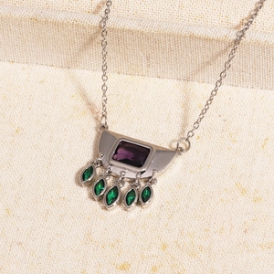 Detail of silver necklace with purple rectangle gemstone and five green teardrop tassels