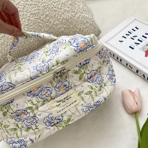 Detail of white quilted cosmetic bag with blue floral pattern and sturdy double zippers