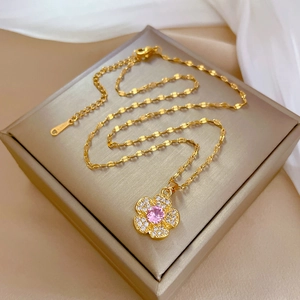 Detailed macro view of a gold flower necklace with pink gemstone on a luxury jewelry box
