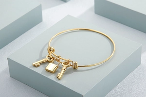 Detailed view of a gold stainless steel wire bracelet featuring lock and key charms