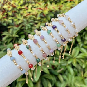 Detail of colorful gemstone beads and baroque pearl bracelets with religious charms