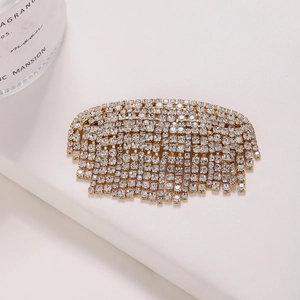 Barrette dorée élégante avec strass brillants et pampilles sur un fond blanc épuré