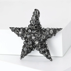 Detailed view of a dark grey star-shaped brooch with faceted crystals on white stone base