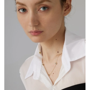 Close-up of gold titanium necklace with colorful inlaid gemstones on a white shirt