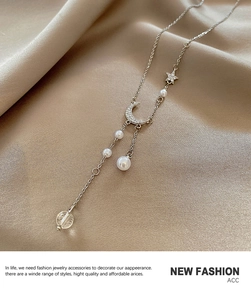 Detail of silver long chain necklace featuring moon, star, and pearl pendants on silk