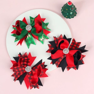 Close-up of three festive Christmas bow hair clips with rhinestones on a white display tray