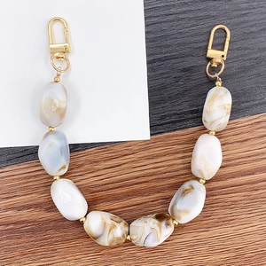 Acrylic marble patterned beads handbag chain with gold metal buckles on wood surface