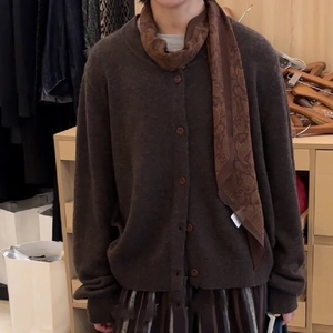 Detail of a brown knit cardigan with matching paisley pattern scarf necklace accessory