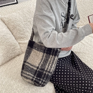Close-up of plush black and white checkered crossbody bucket bag for autumn winter season