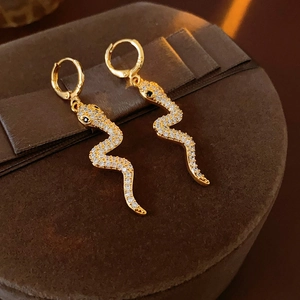 Detailed shot of gold-plated snake hoop earrings with micro-set zircon on velvet