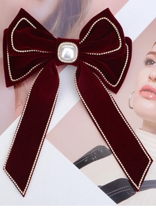 Detail of red velvet bow hair clip with gold beads and a square pearl accent